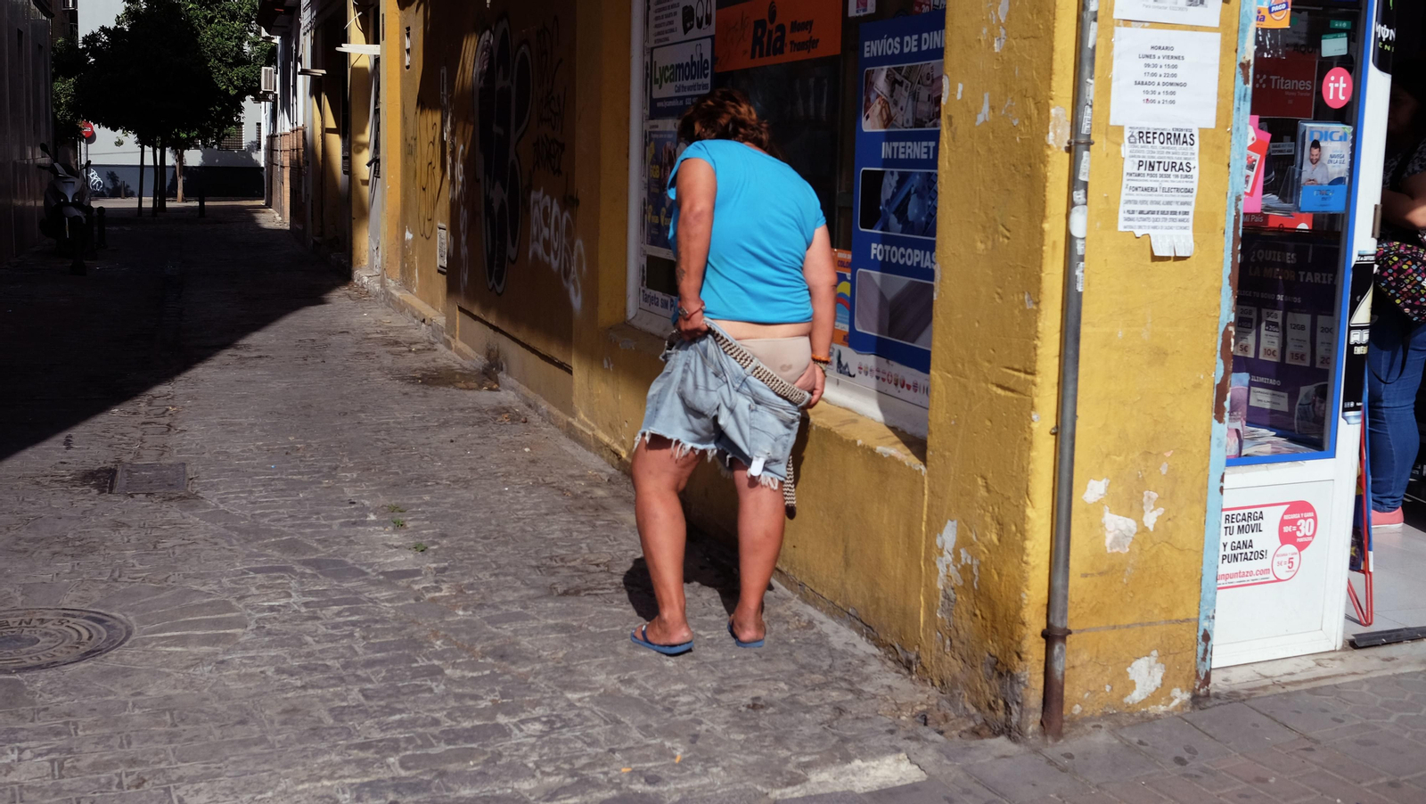 Una mujer se sube el pantalón en una calle de la Macarena.