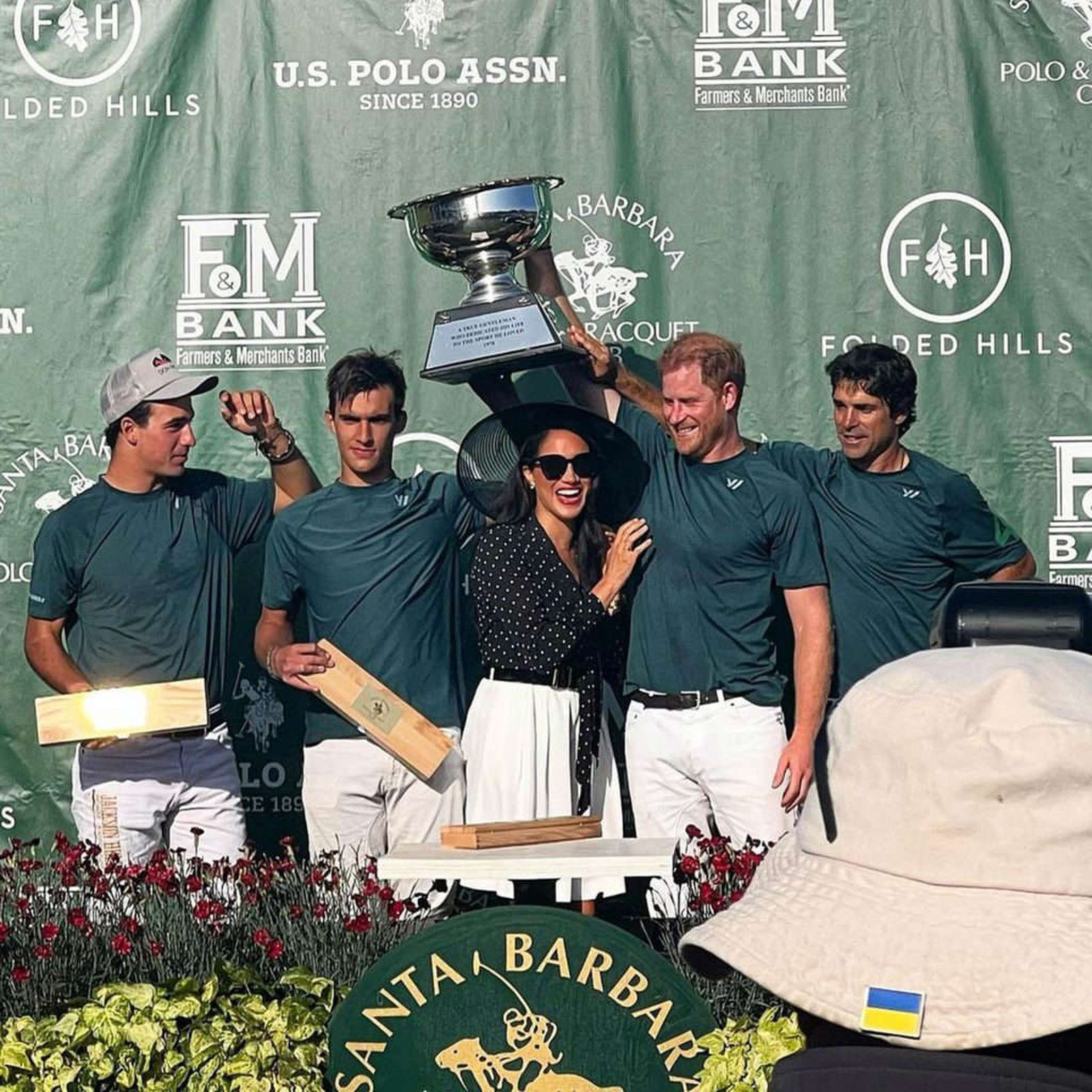 El príncipe Enrique y su esposa, tras hacerle entrega ella al equipo de él de su trofeo.