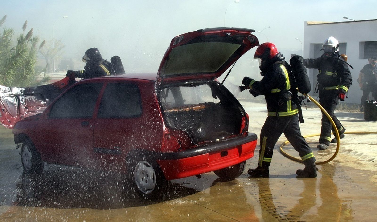 Varios bomberos apagan un coche incendiado