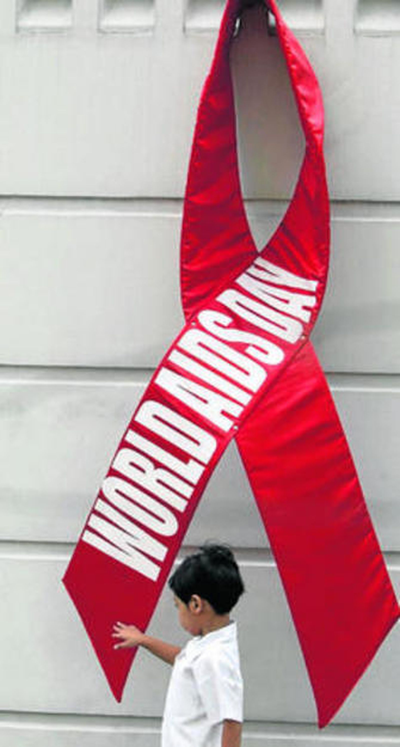 Un niño pasa delante de un crespón rojo del edificio de la OMS.