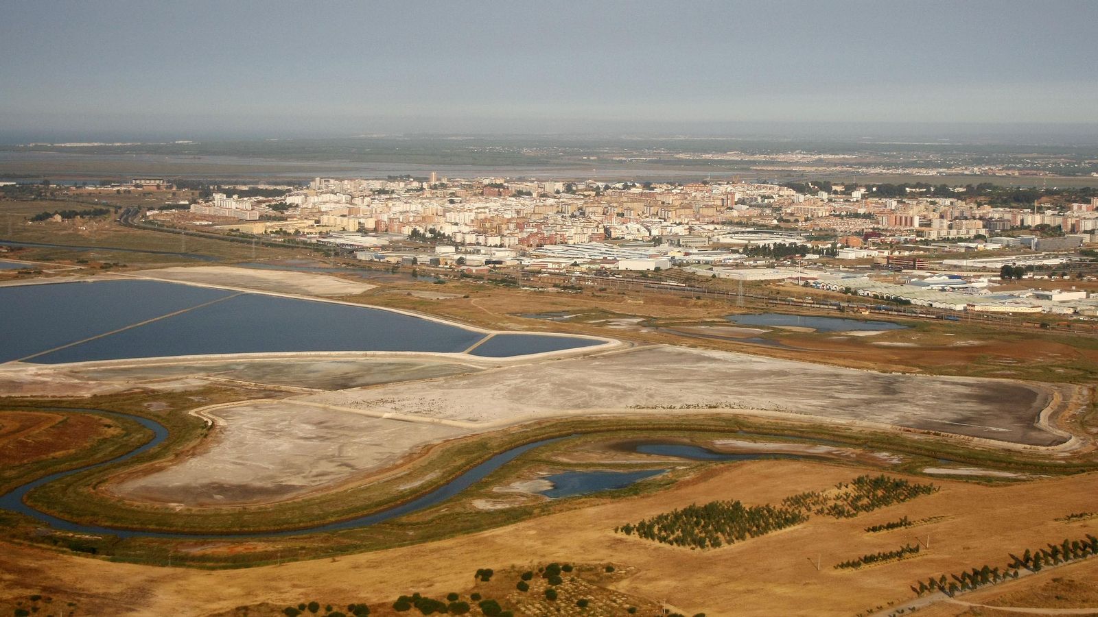Balsas de fosfoyeso con la ciudad al fondo.