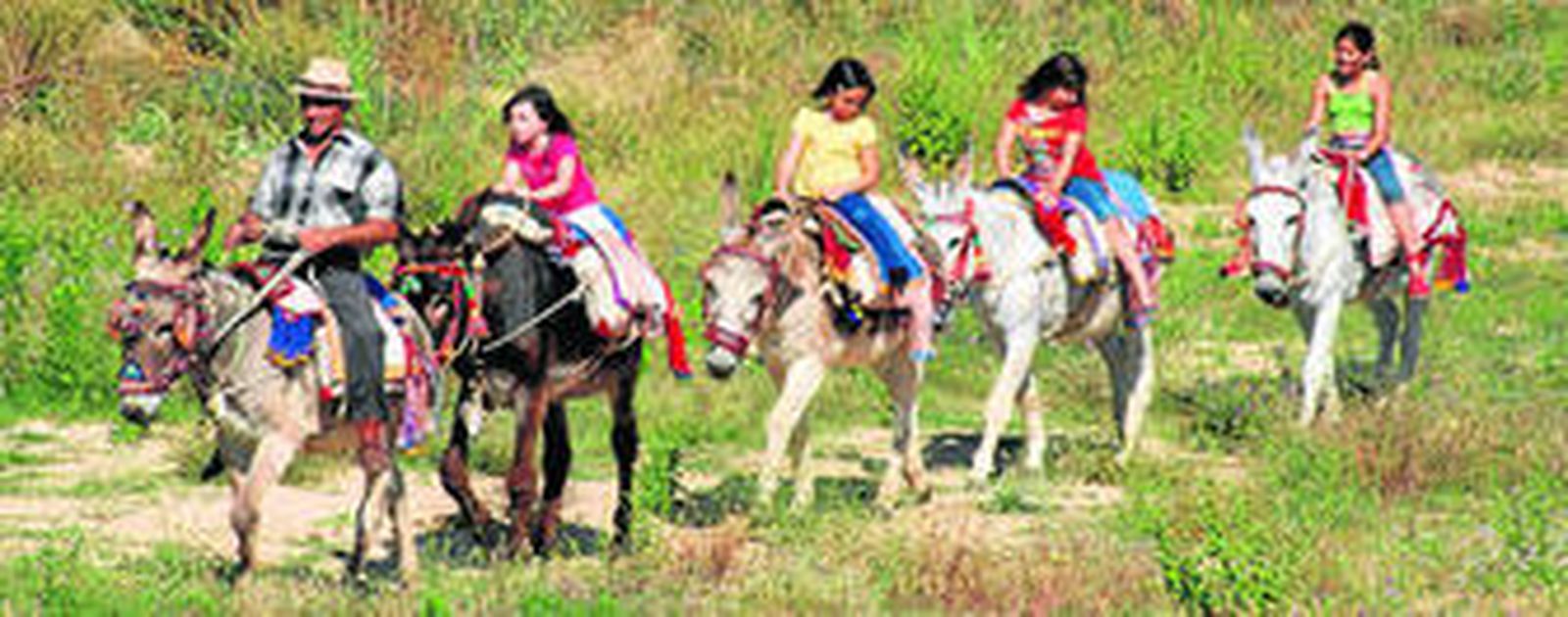 Varios niños realizando la ruta en burro por uno de los senderos de La Janda.