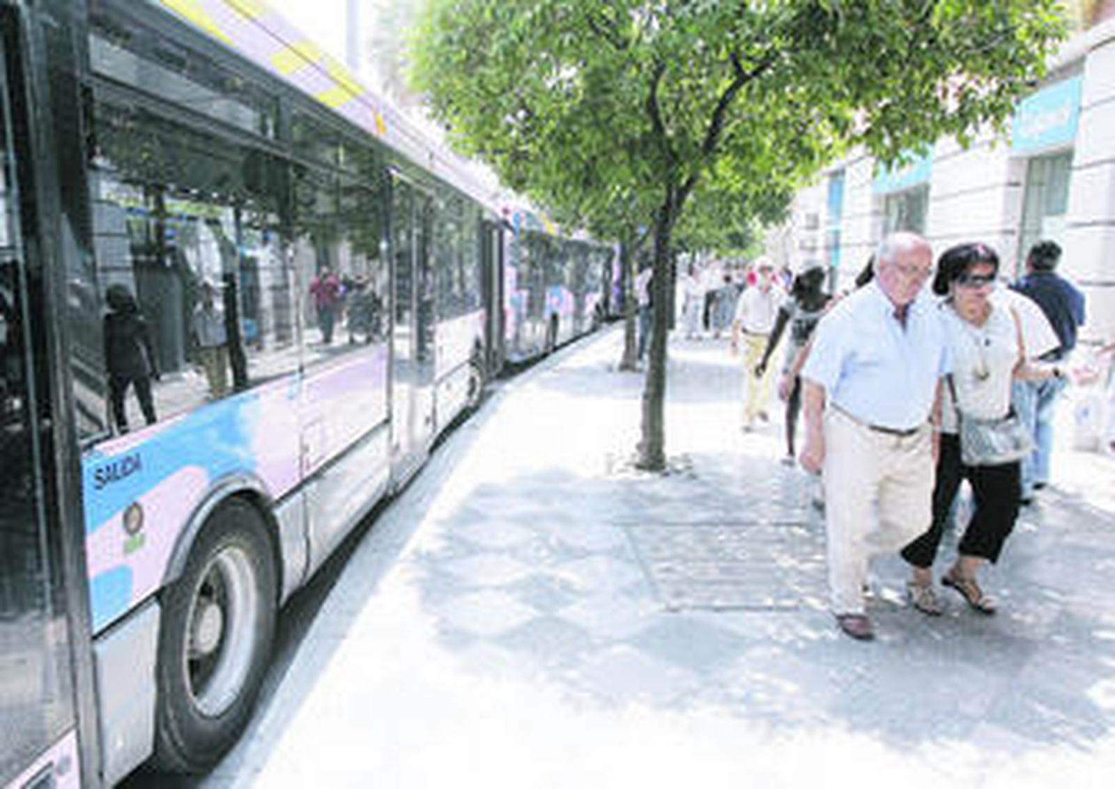 Una pareja pasea ante unos autobuses estacionados en la Rotonda de los Casinos.