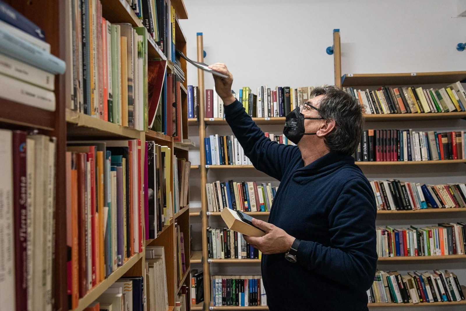 El presidente de la ONG colocando ejemplares en la estantería de la librería.