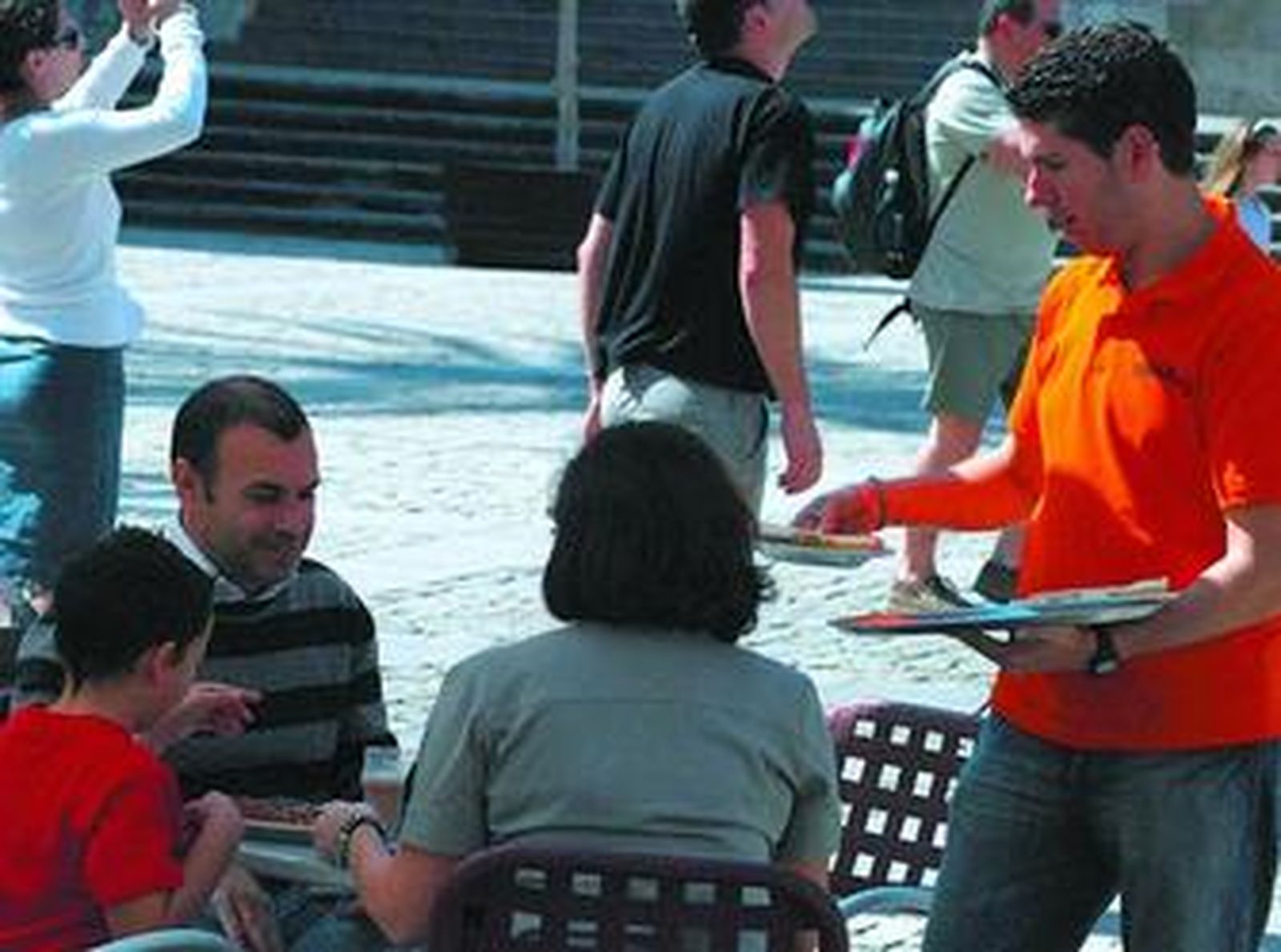 Un camarero sirve a una mesa en una plaza de la capital gaditana.