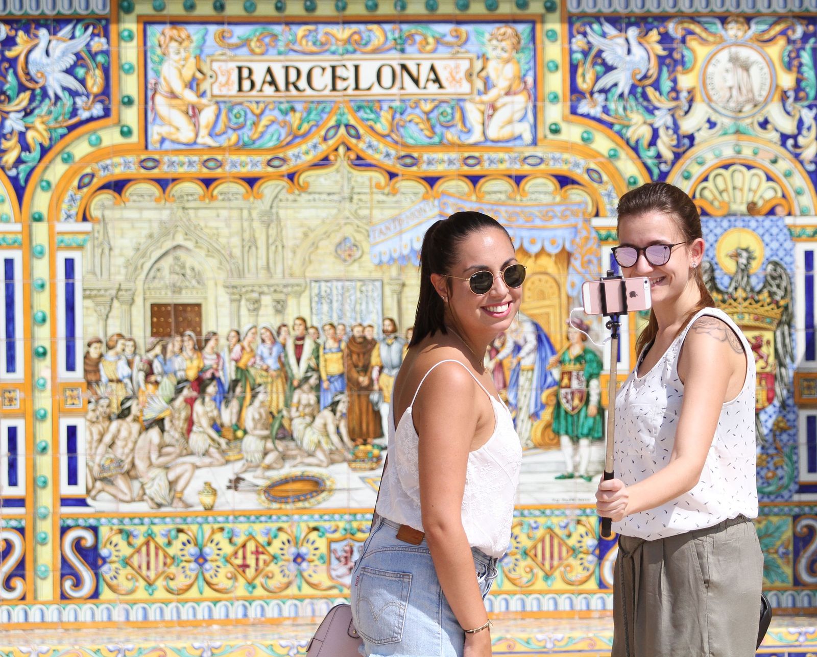 Dos jóvenes se fotografían ante el banco de Barcelona en la Plaza de España / BELÉN VARGAS