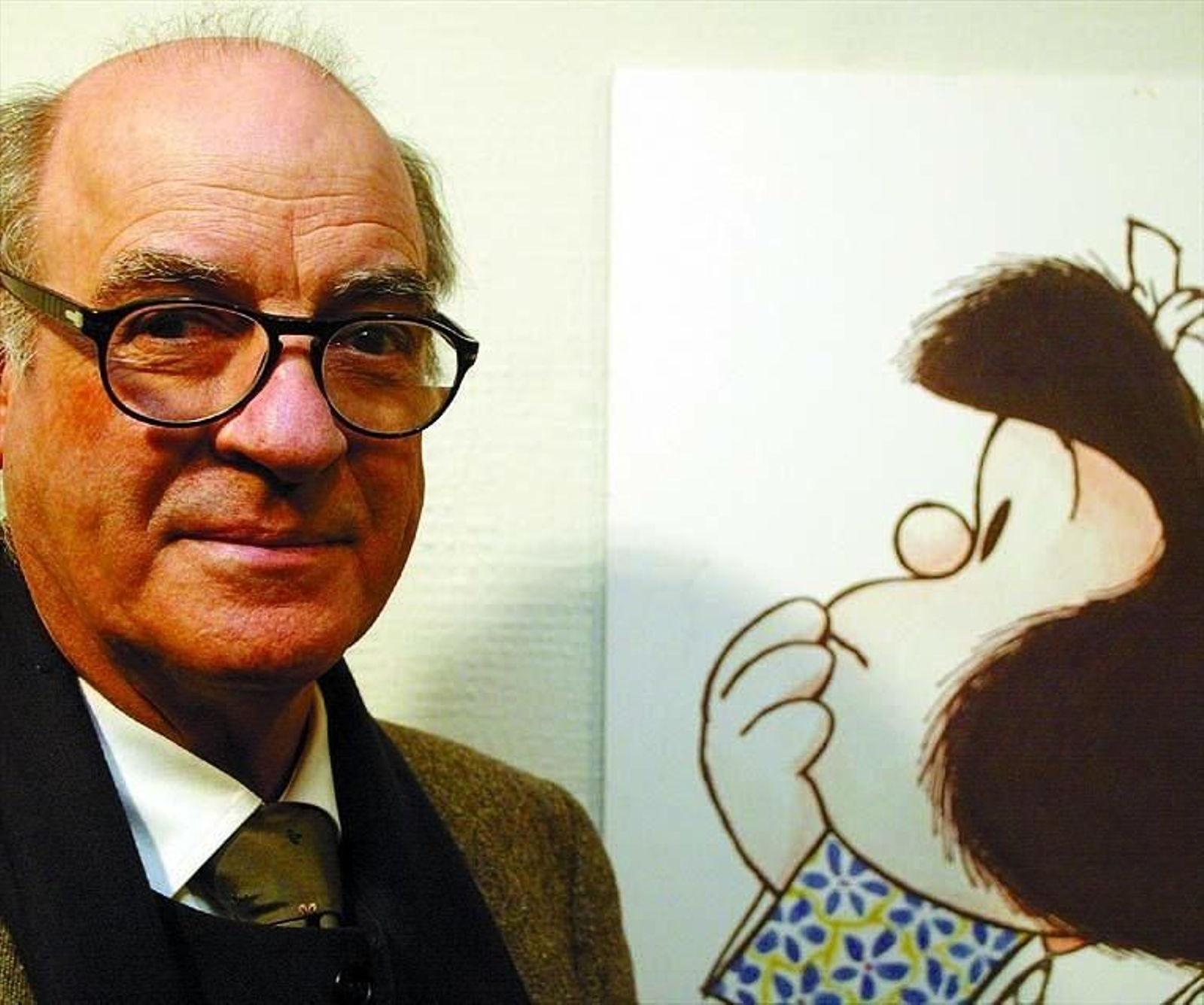 El dibujante y humorista gráfico Quino junto a un dibujo de Mafalda, la criatura que le dio fama mundial.