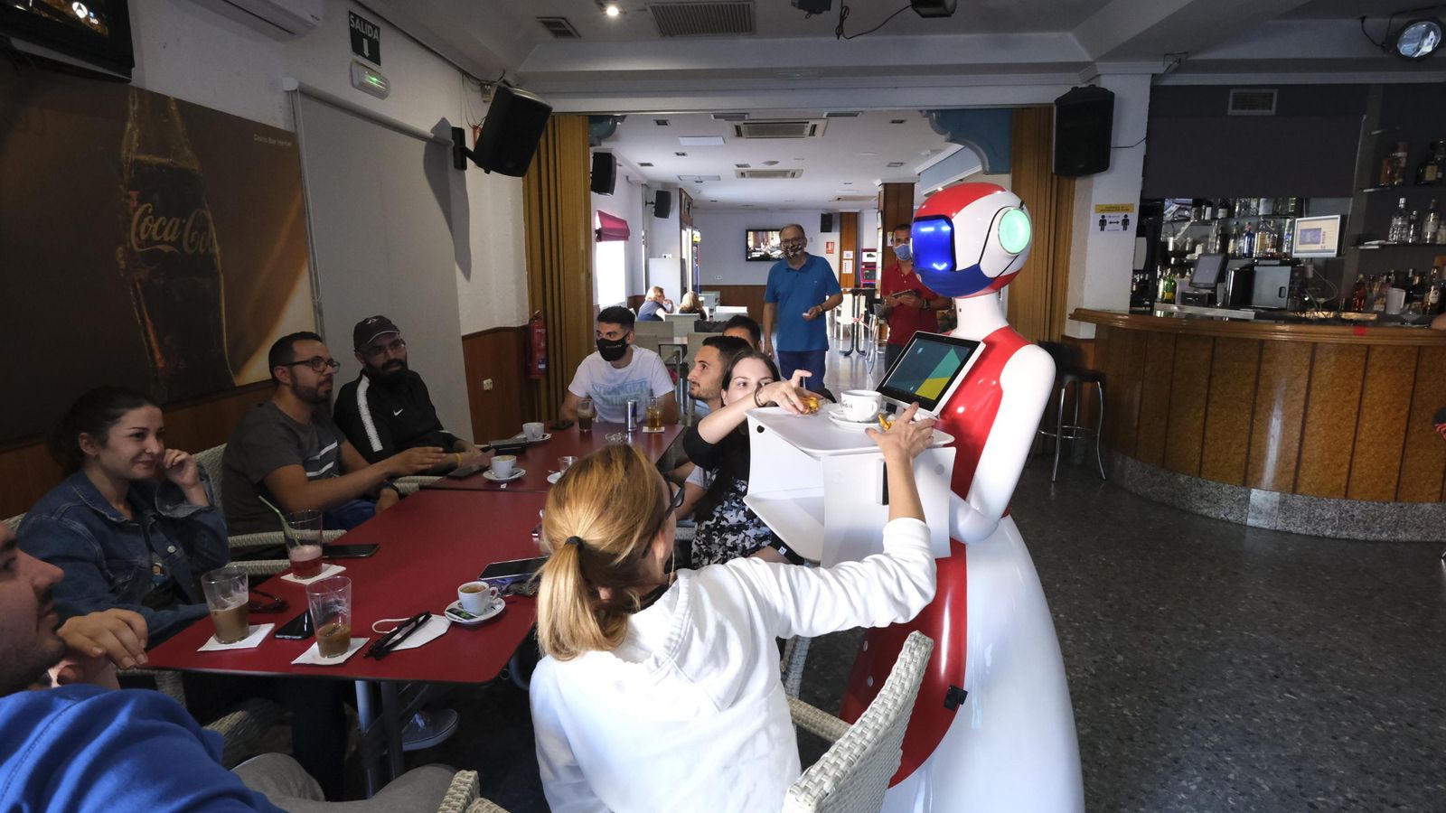 Un grupo de clientes coge sus consumiciones de la bandeja de Herlbelita.