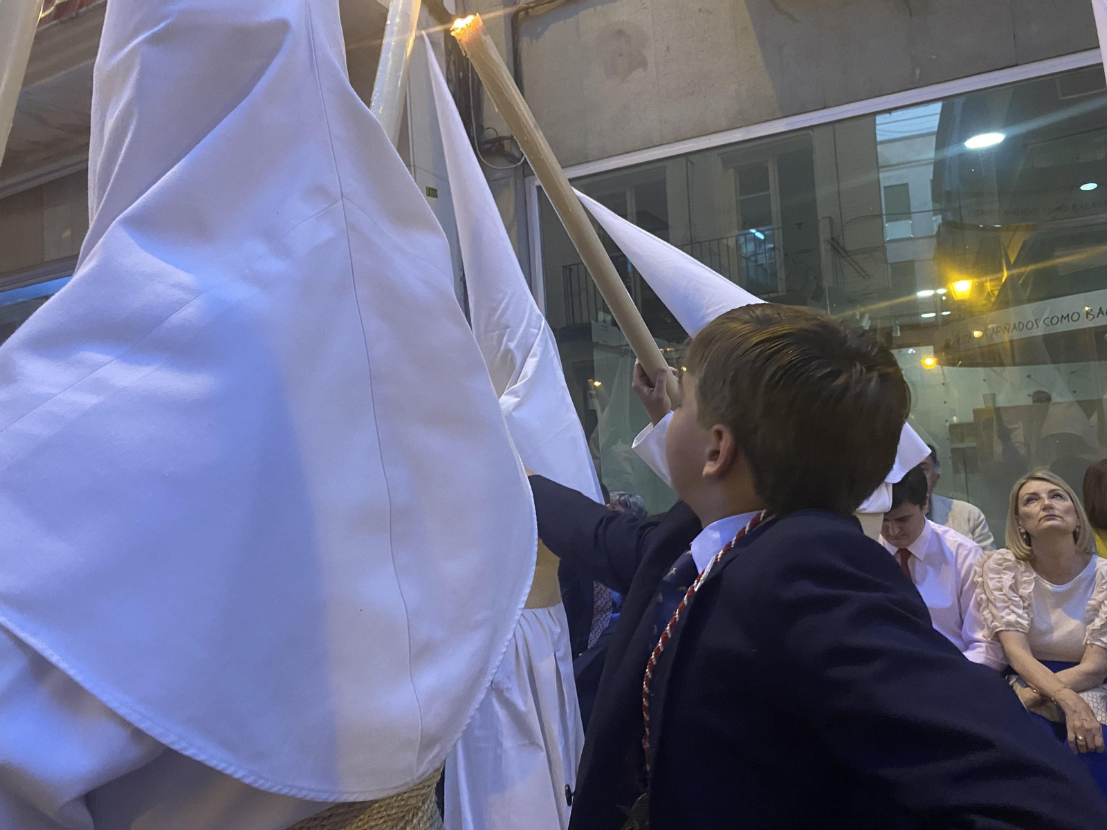 Un niño coge cera de los nazarenos de la Amargura.