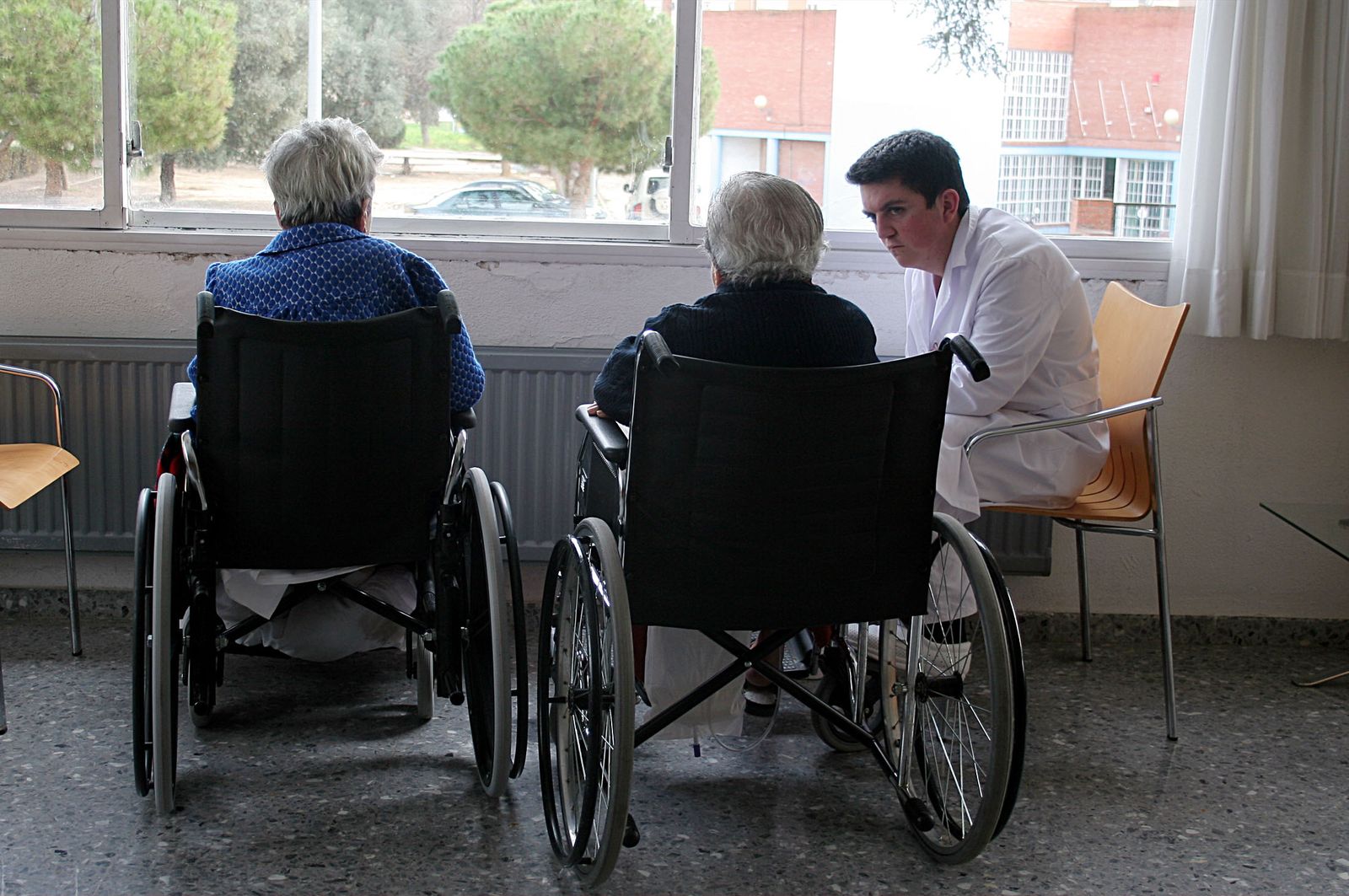 Dos ancianas con un cuidador en una residencia de la tercera edad.