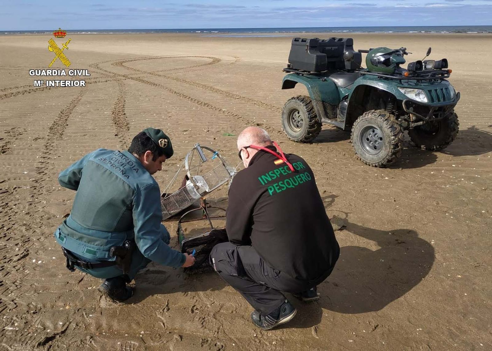 Agentes de la Guardia Civil e Inspección Pesquera con un rastrillo decomisado.