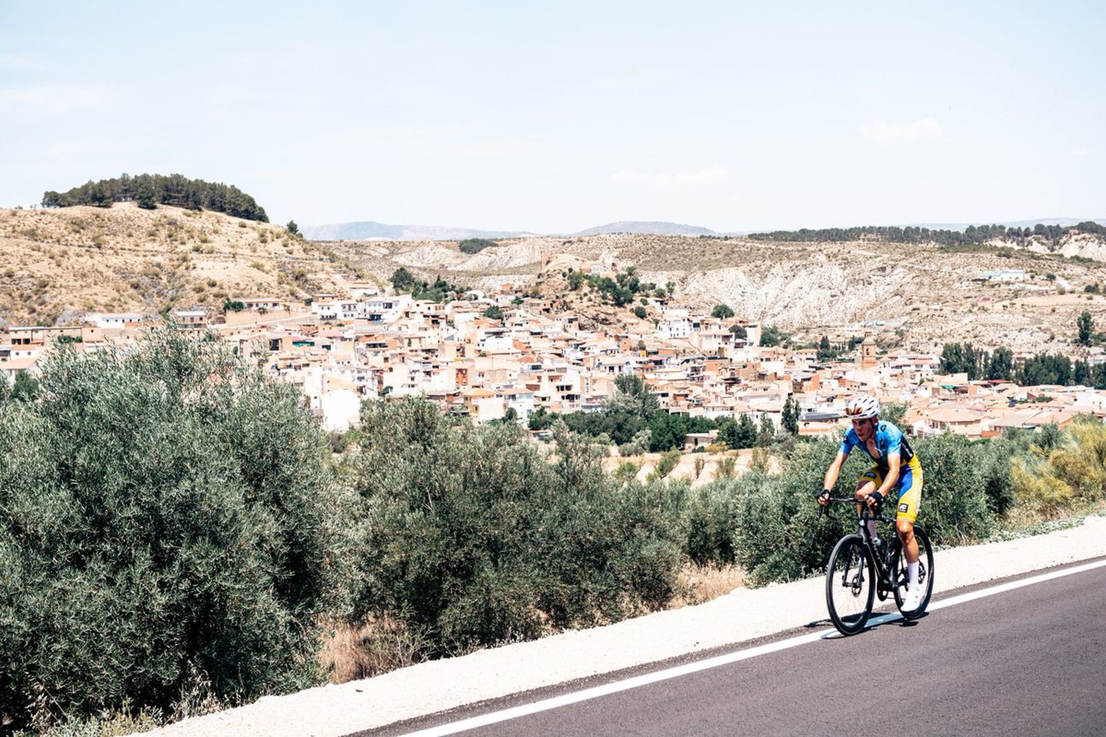 Un ciclista en pleno esfuerzo con un pueblo granadino de fondo.