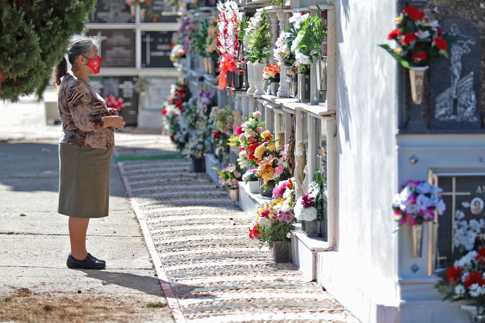 Una mujer deposita flores frente a una tumba.