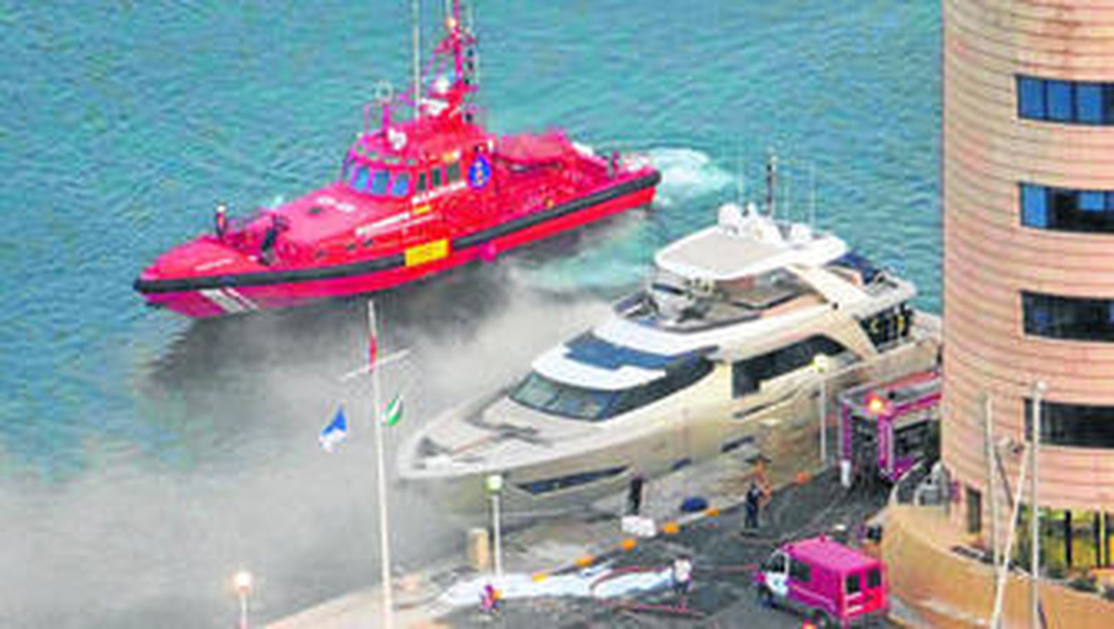 El lujoso yate en llamas junto a la embarcación de Salvamento Marítimo que lo remolcó hasta la capital.
