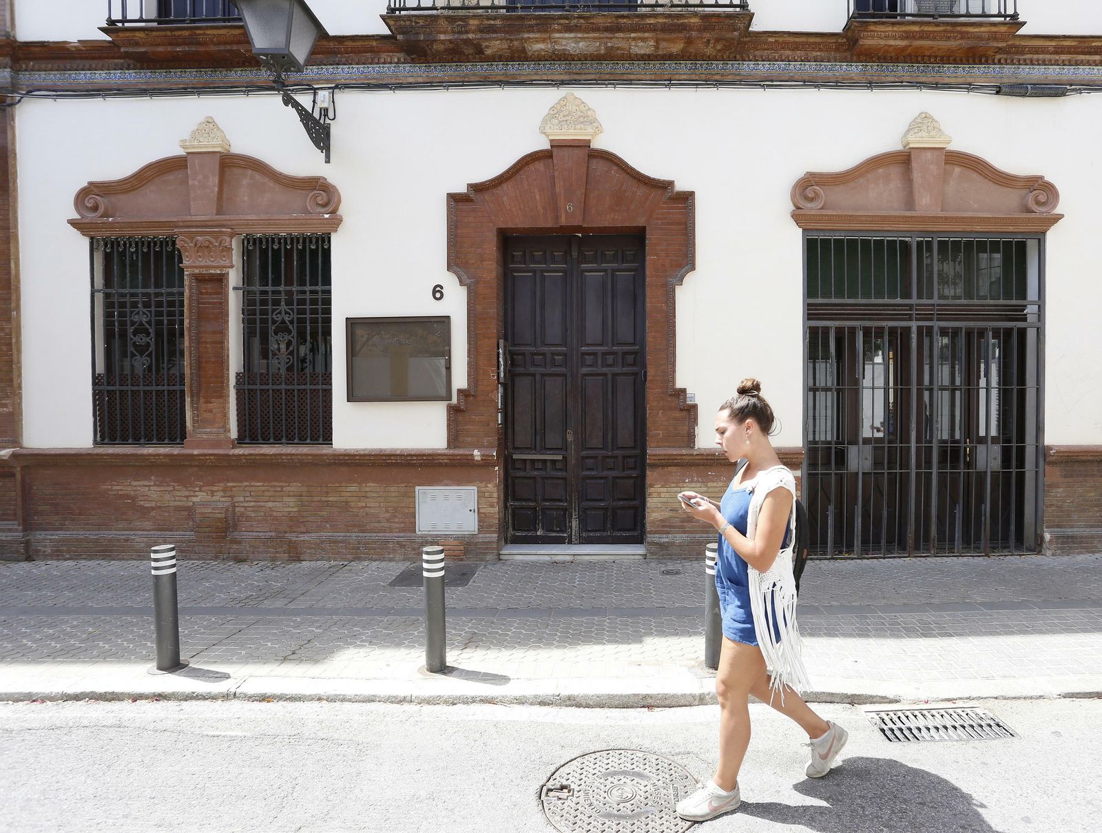 Una joven consulta el móvil a su paso por el inmueble, que se encuentra en el número 6 de la calle Padre Manjón.