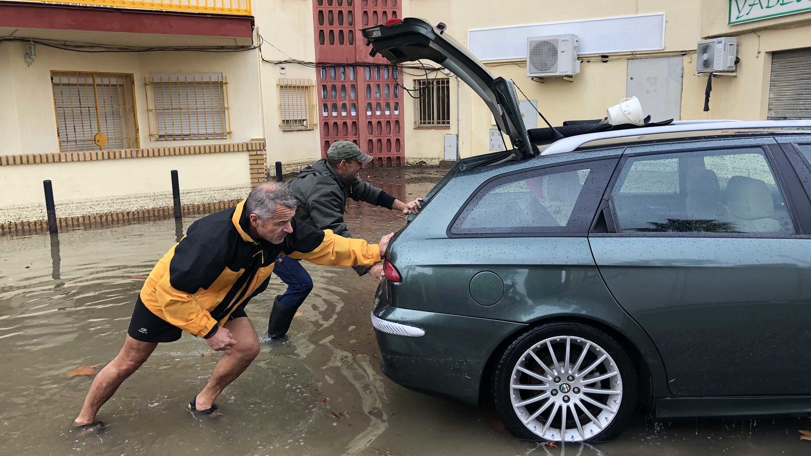 Dos hombres intentan sacar un vehículo de una balsa de agua
