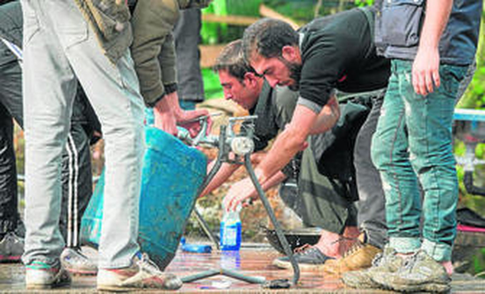Un grupo de refugiados toma agua de unos grifos instalados en el campamento de Calais.