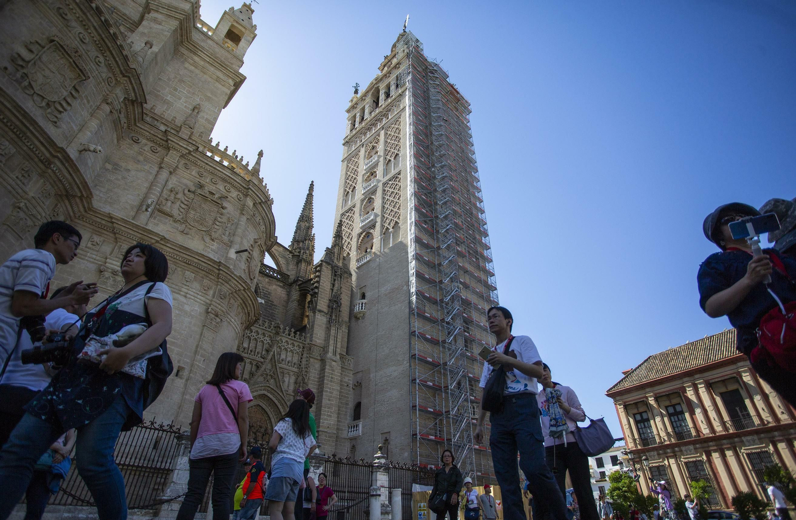 Un grupo de turistas pasea ante la Catedral y la Giralda.