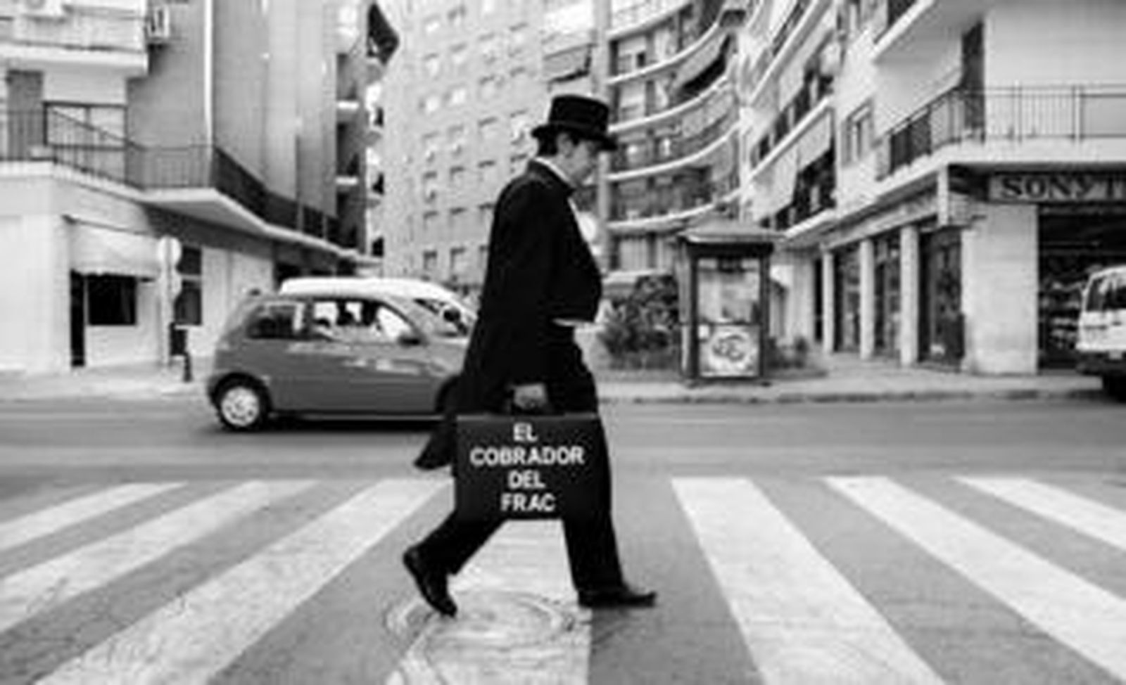 El cobrador del frac cruza un paso de peatones en Los Remedios para investigar a un moroso.