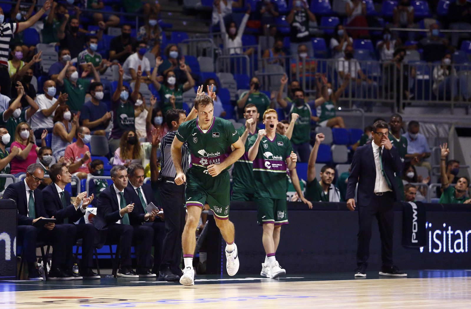 Tim Abromaitis celebra, con la afición y el banquillo de fondo, un triple.