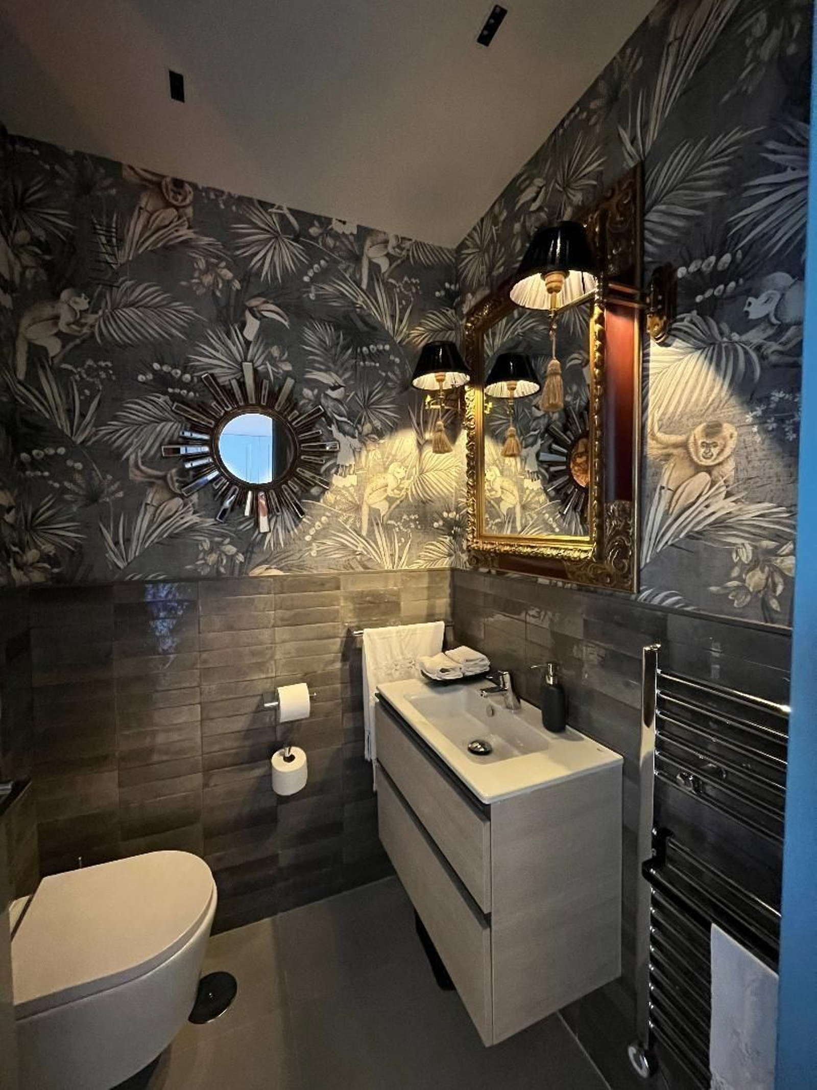 Baño. Utiliza para sus paredes un  papel de la firma Arte de París que recrea escenas de arbolados de la selva