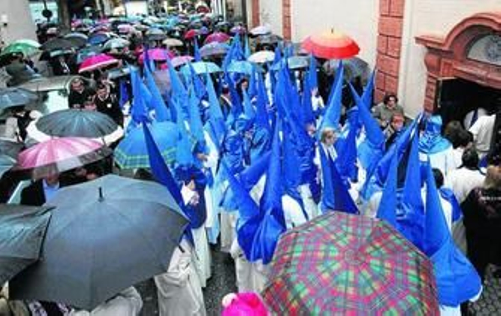 Los nazarenos de Montserrat hacen cola para entrar en el templo entre un mar de paraguas, antes de que la hermandad decidiera no salir.