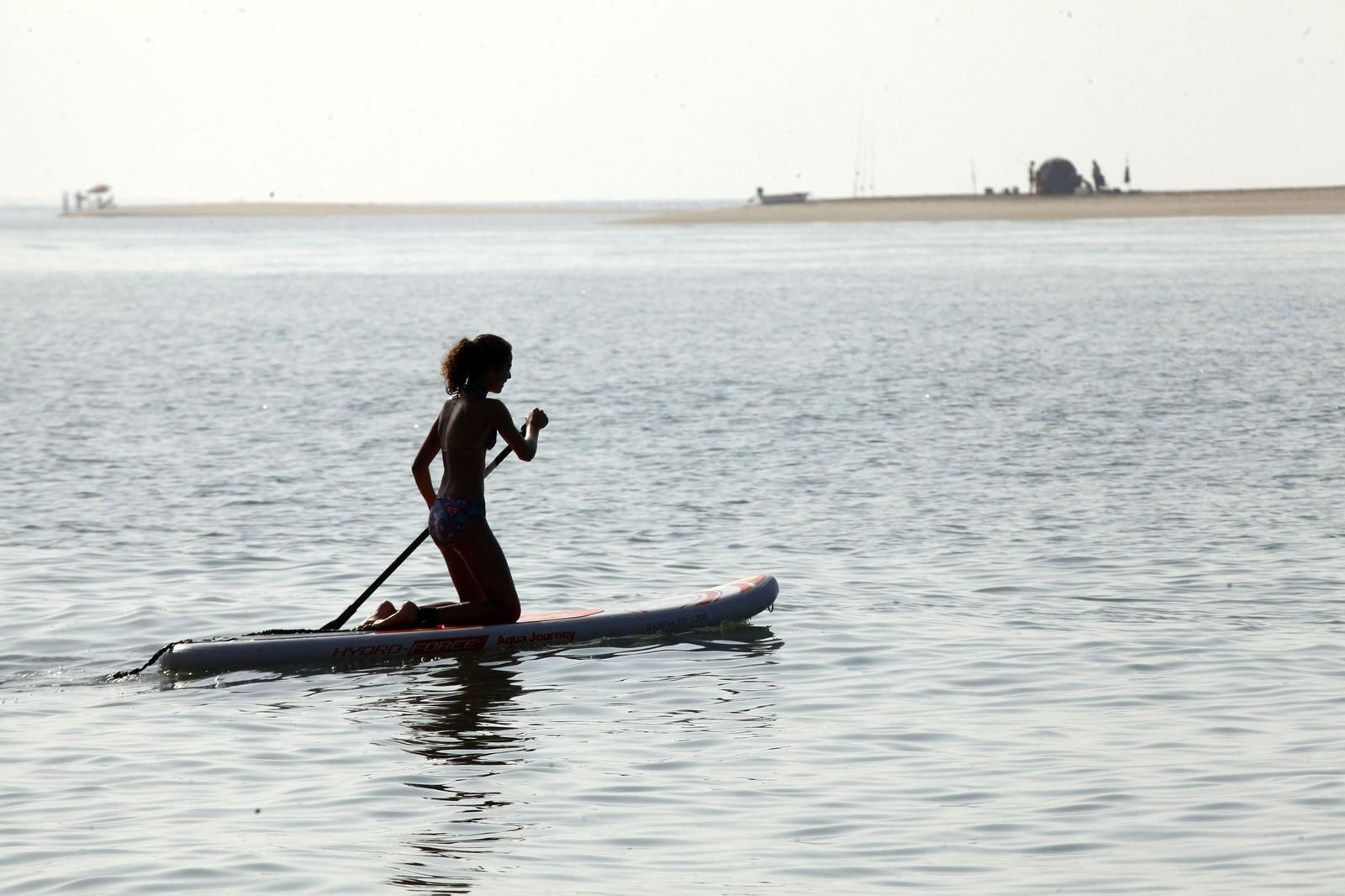 Una joven practica pádel surf en una playa de la costa onubense