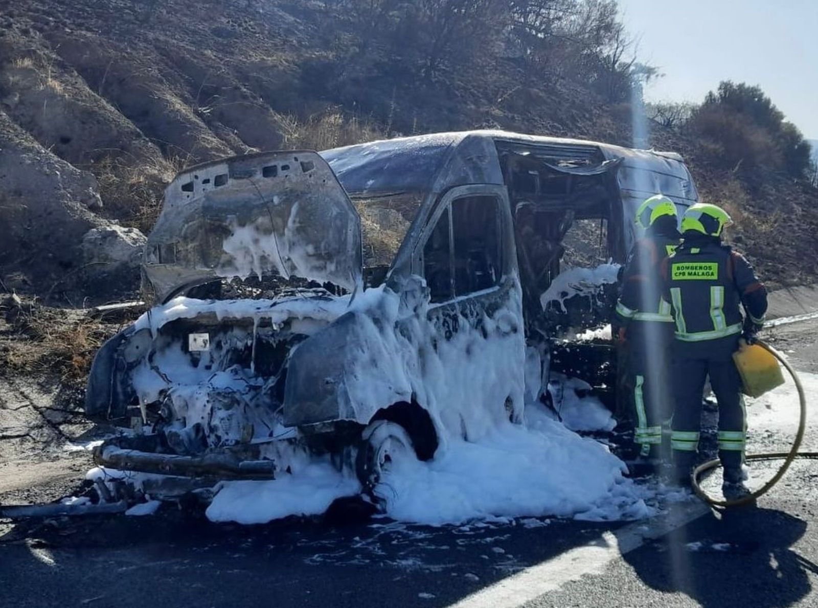 Bomberos sofocando las llamas de la ambulancia.