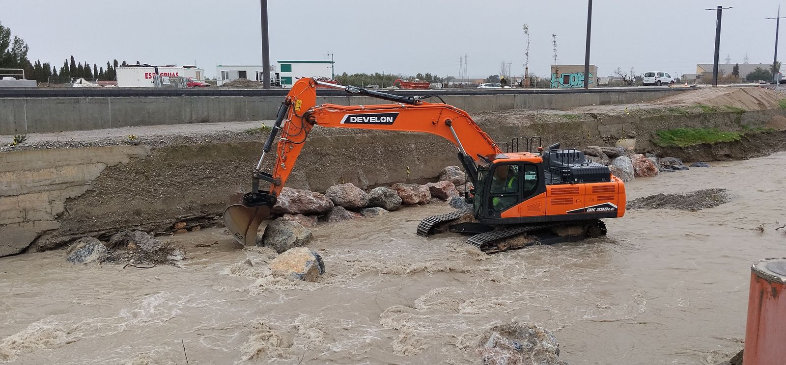 Un brazo excavadora trabaja para colocar la escollera en río Dílar
