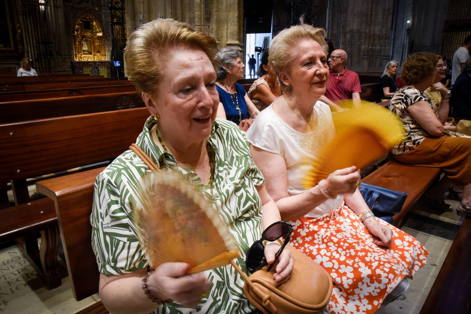 Dos mujeres se abanican el Día de la Asunción en la Catedral de Sevilla.