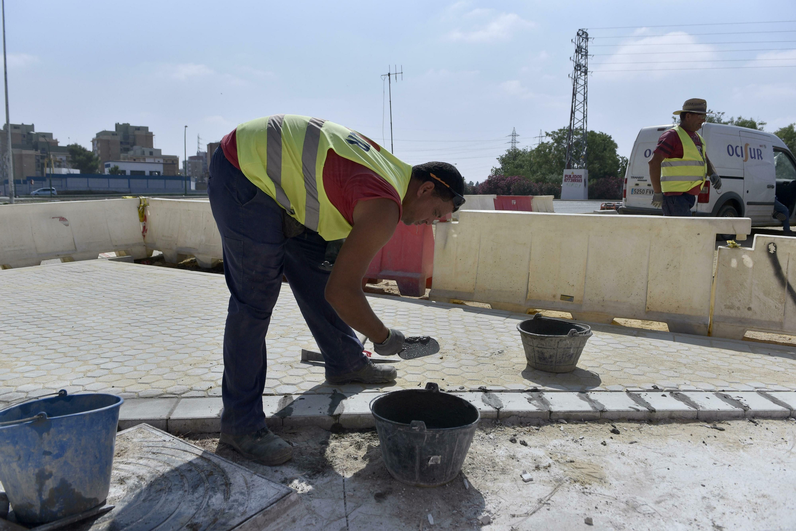 Un albañil pone cemento en un bordillo exterior de hormigón.