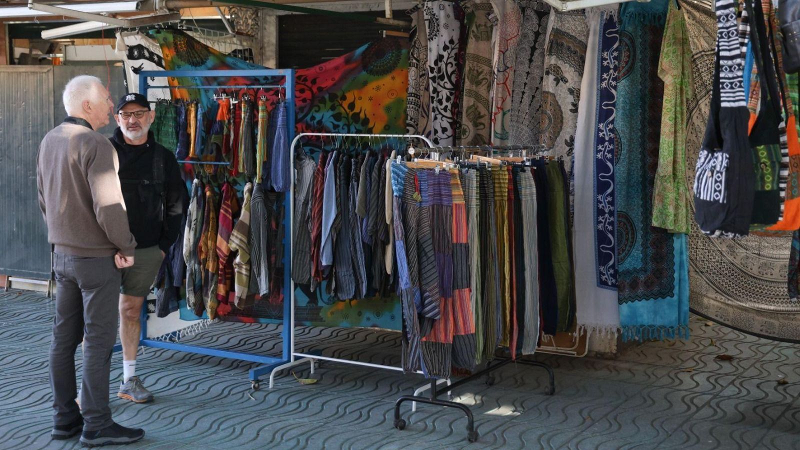 Dos clientes conversan junto a los puestos de venta.