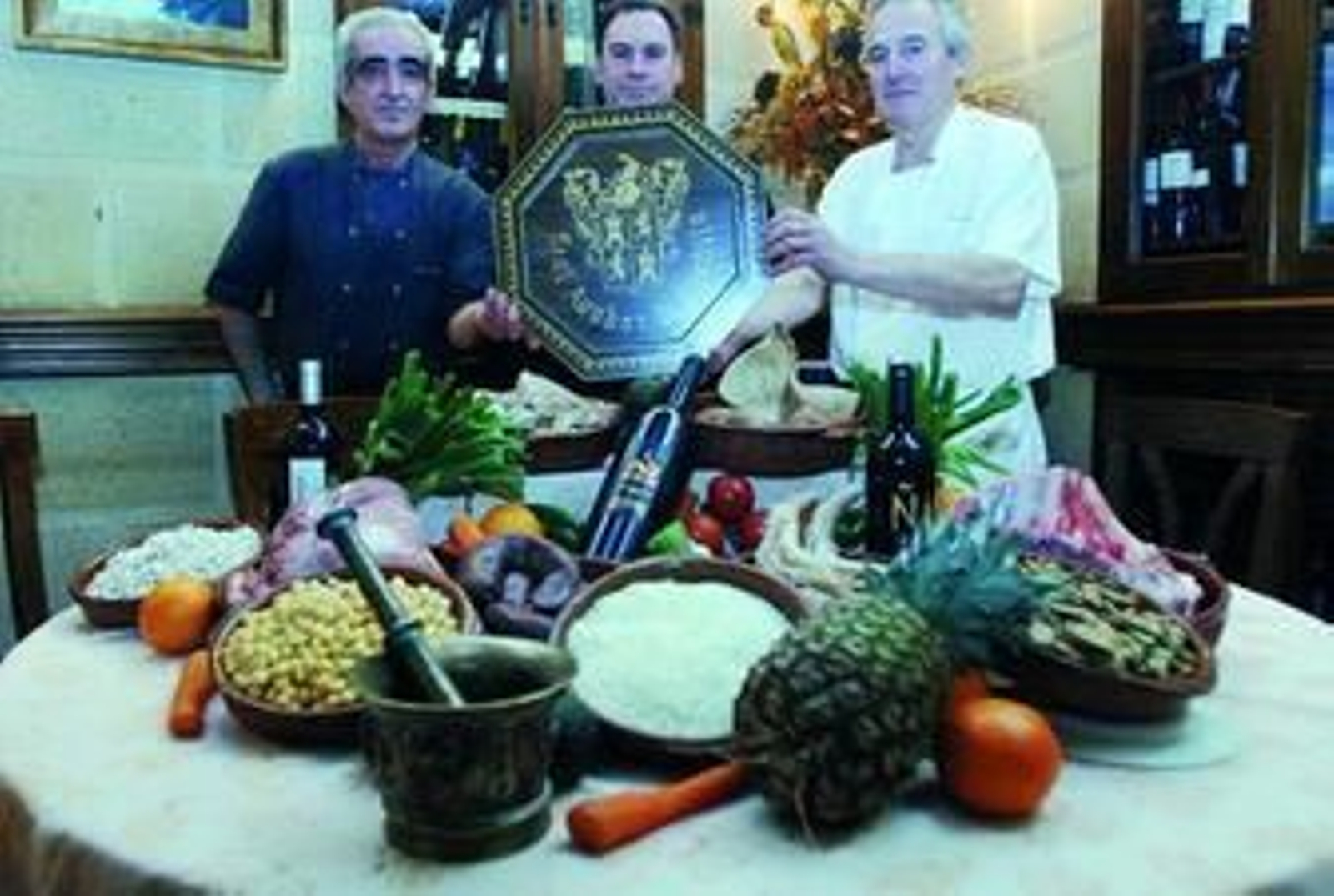 Antonio Moya, en el centro, muestra los ingredientes típicos de la olla  de San Antón que hoy preparará en el restaurante.
