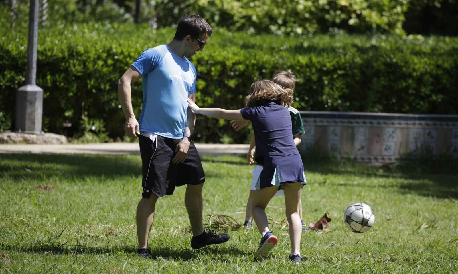 Una imagen de archivo de un padre jugando con sus hijos al aire libre.