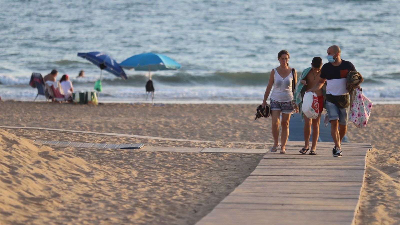 Varias personas disfrutan de la playa de Huelva en pleno otoño.