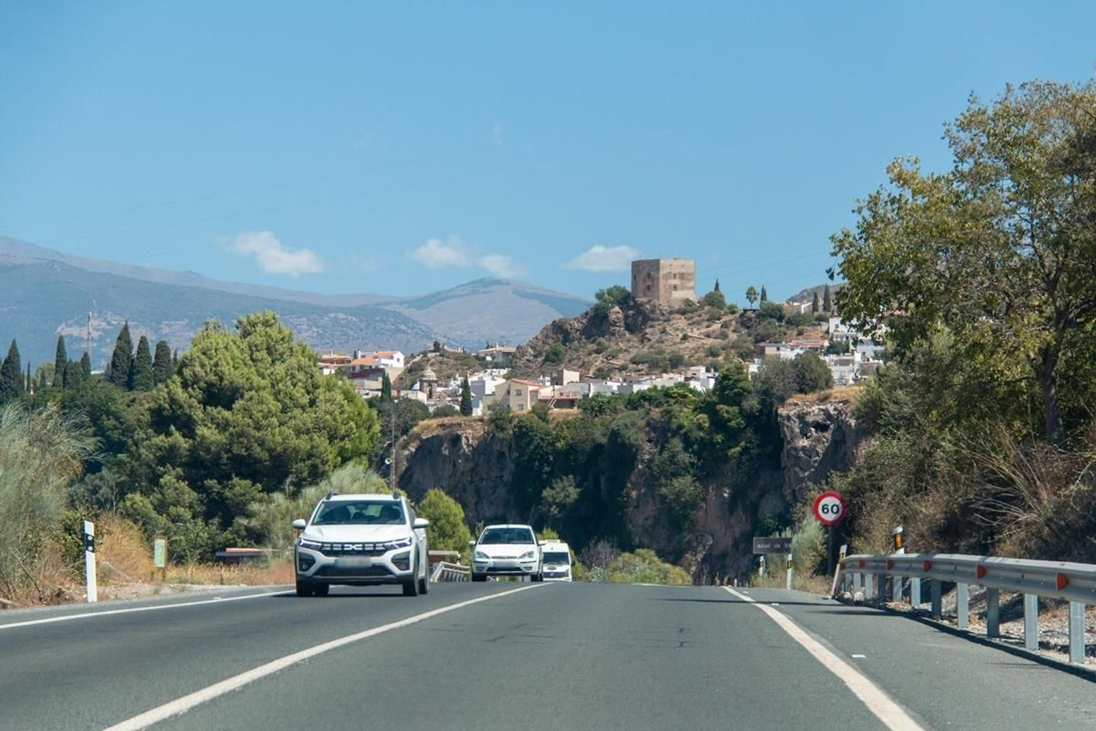 Varios coches circulan por la antigua carretera de la costa con Velez de Benaudalla al fondo.