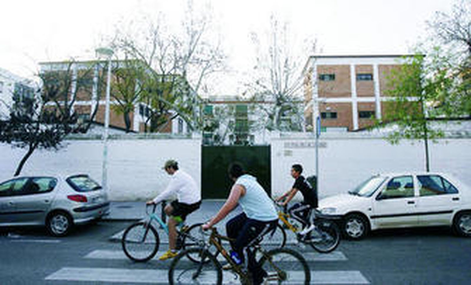 Unos chicos pasean por delante del centro educativo.