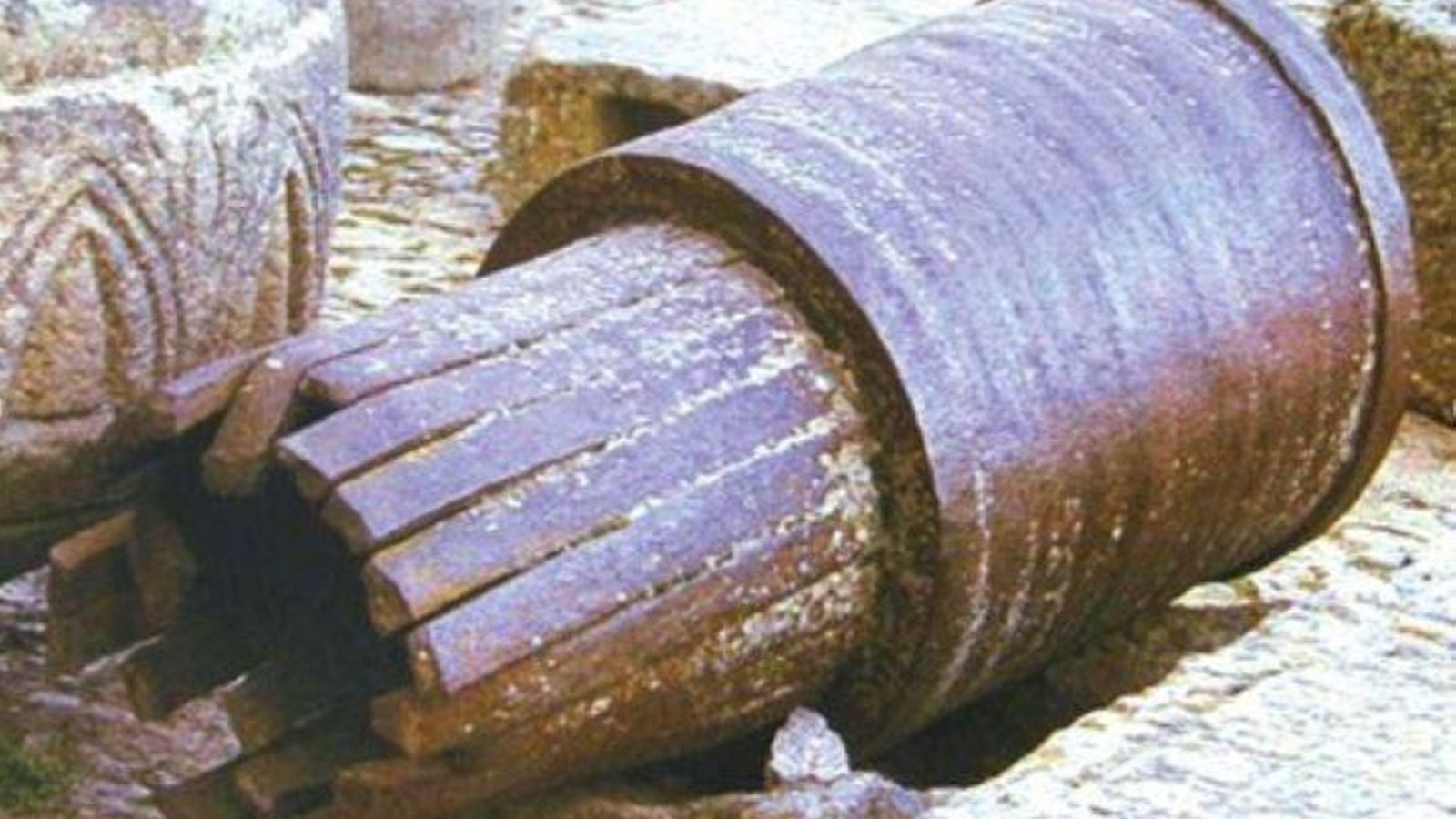 Un antiguo cañón de hierro forjado construido a base de duelas longitudinales reforzadas por aros.