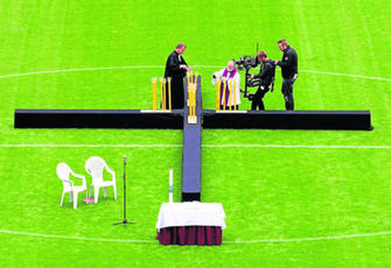 Dos sacerdotes encienden velas en recuerdo de los fallecidos en el estadio de fútbol de la ciudad.