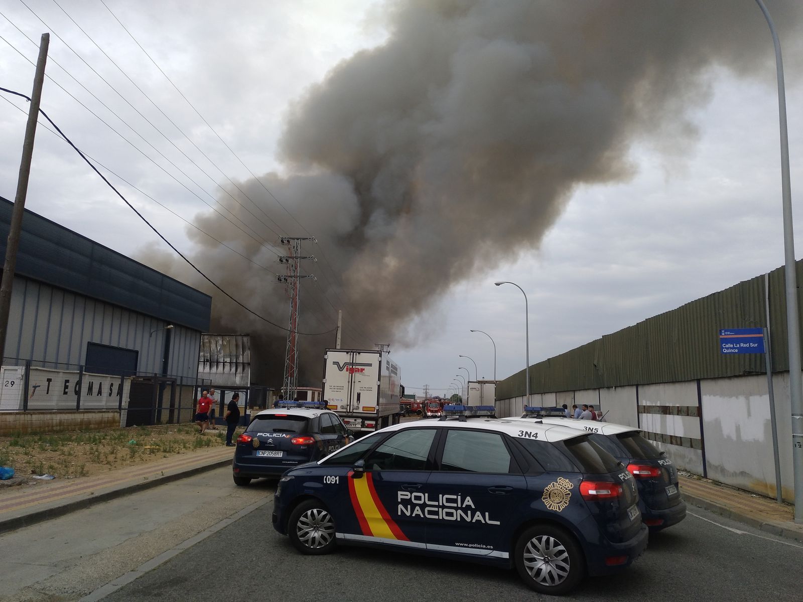 Dos patrulleros de la Policía Nacional con la espectacular columna de humo al fondo.