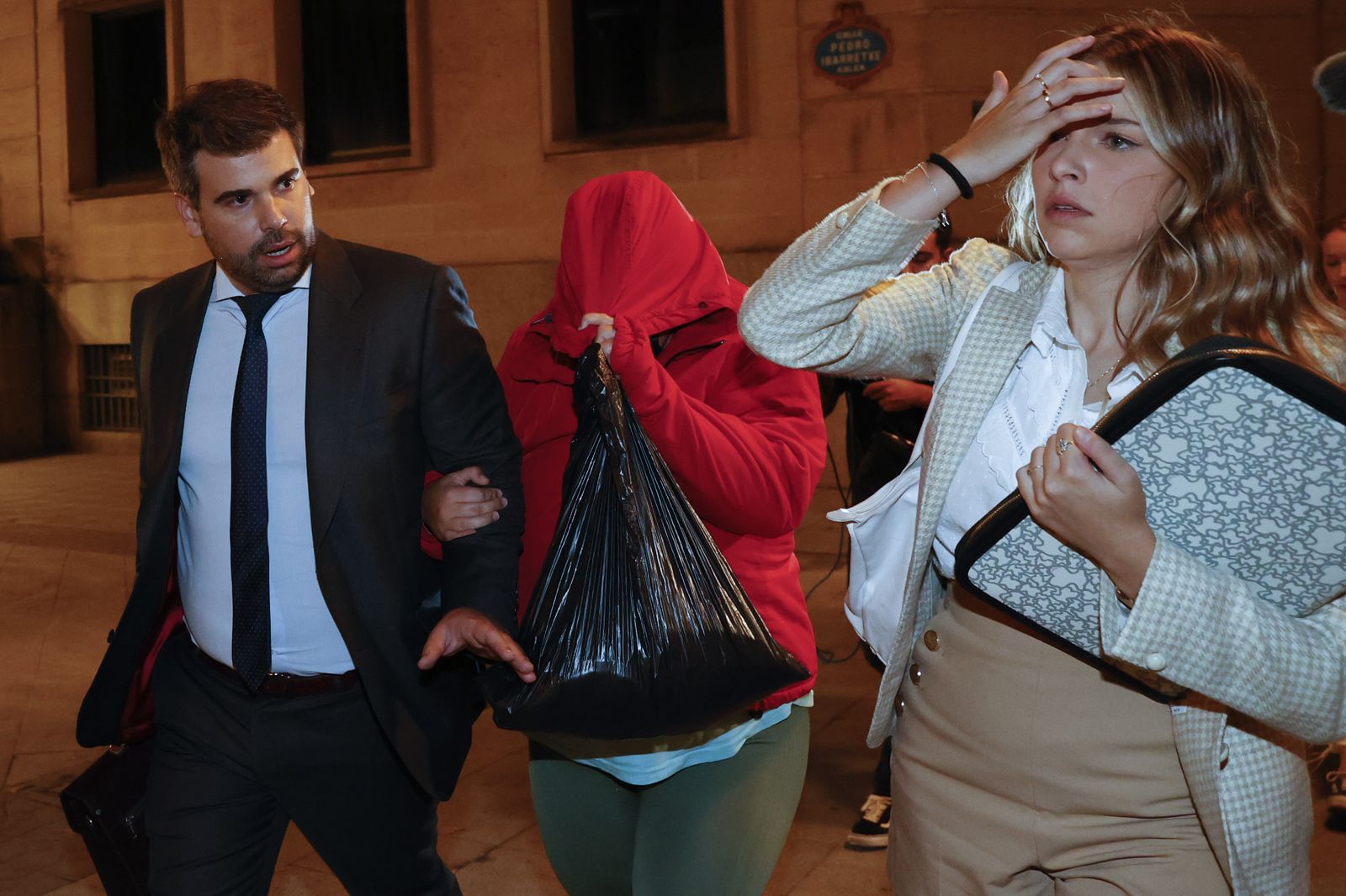 La joven que secuestró el bebé en Bilbao (con la capucha roja) abandona los juzgados acompañada por sus abogados.