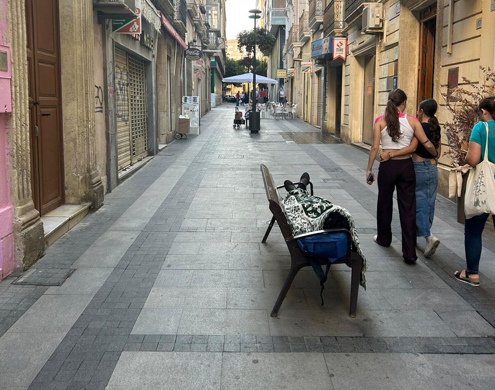 Una persona duerme en un banco de una de las calles perpendiculares al Paseo.