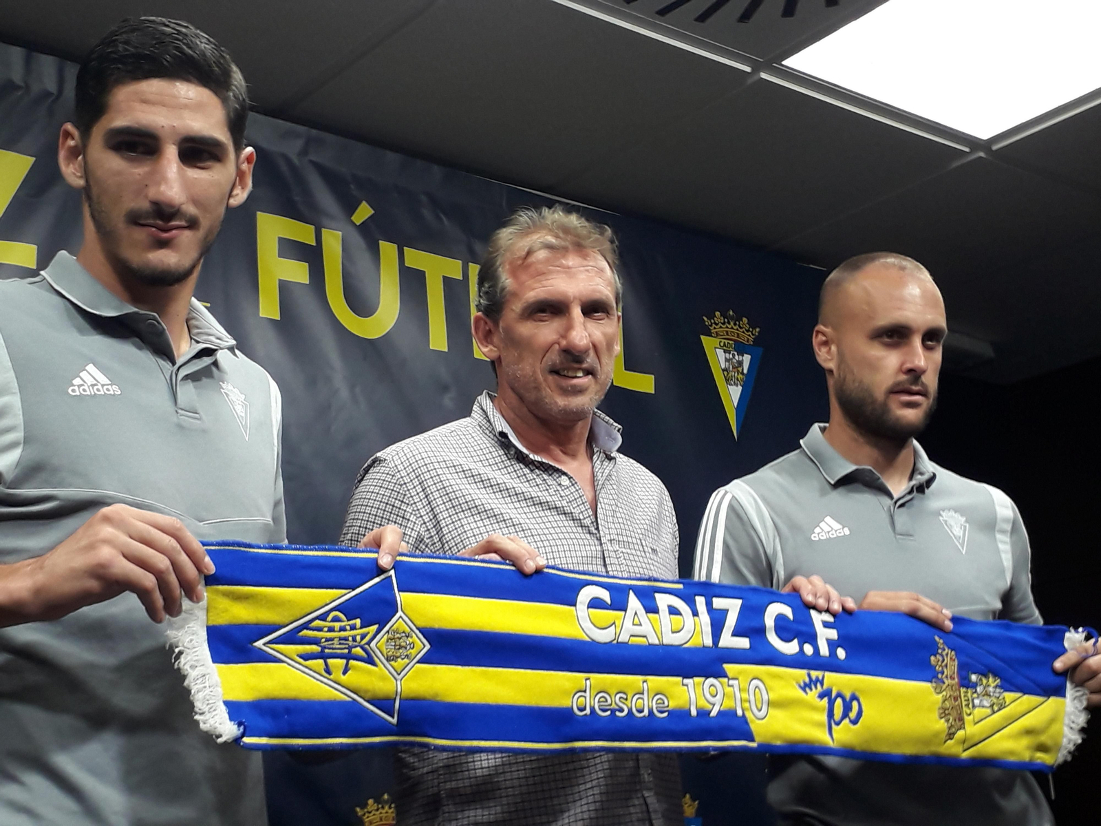 Yann Bodiger, Óscar Arias y Juan Cala sujetan una bufanda del Cádiz en la sala de prensa del Ramón de Carranza.
