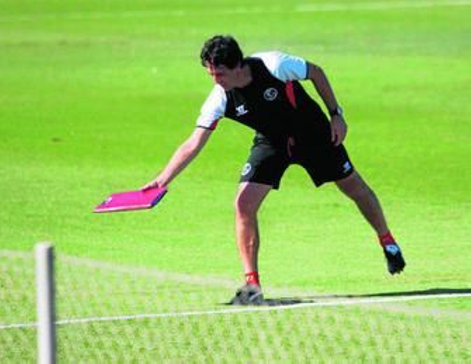 Unai Emery deja una carpeta en el césped de la ciudad deportiva durante un entrenamiento.