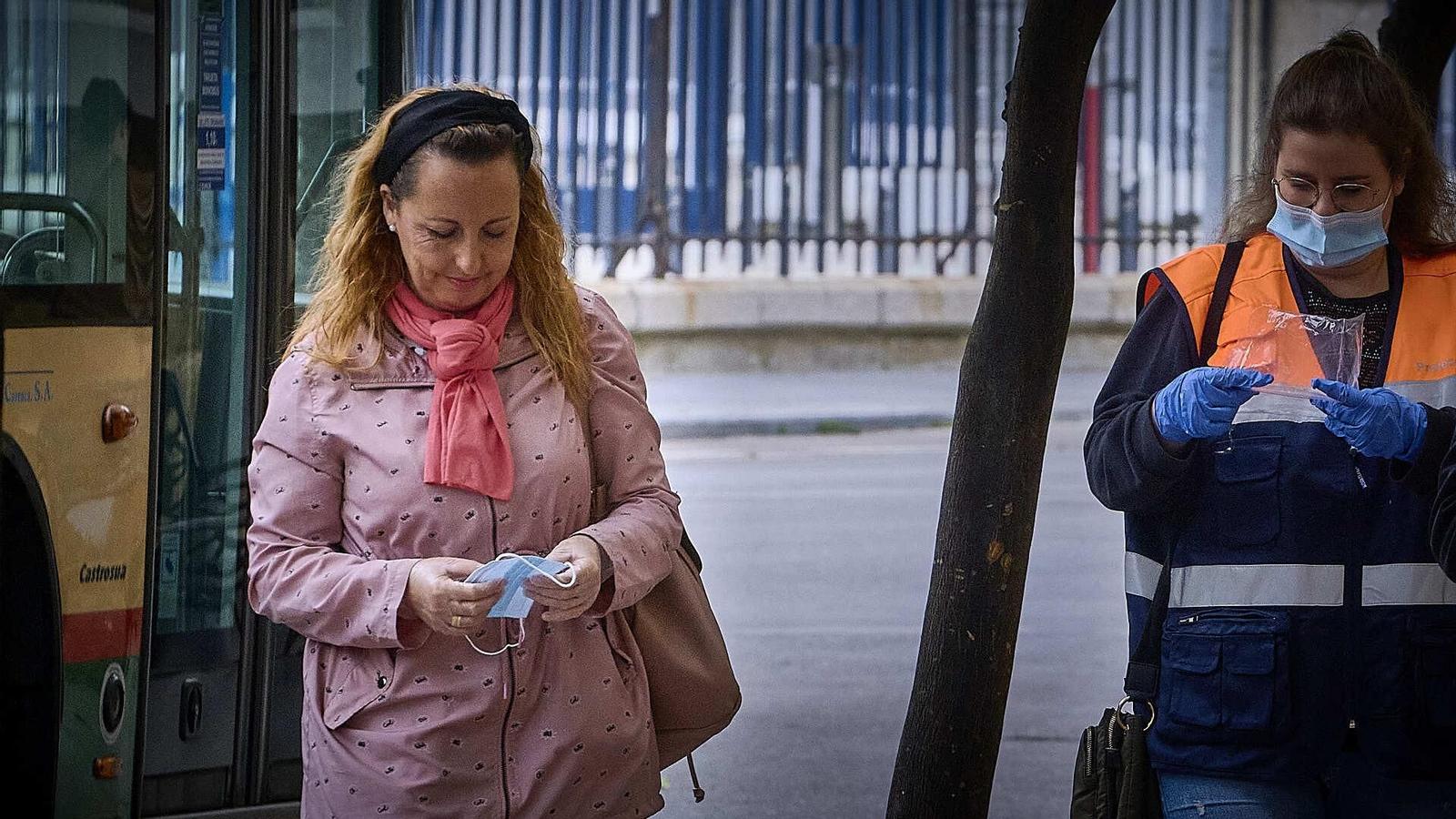 Una mujer observa la mascarilla que acaba de recibir de una voluntaria de Protección Civil