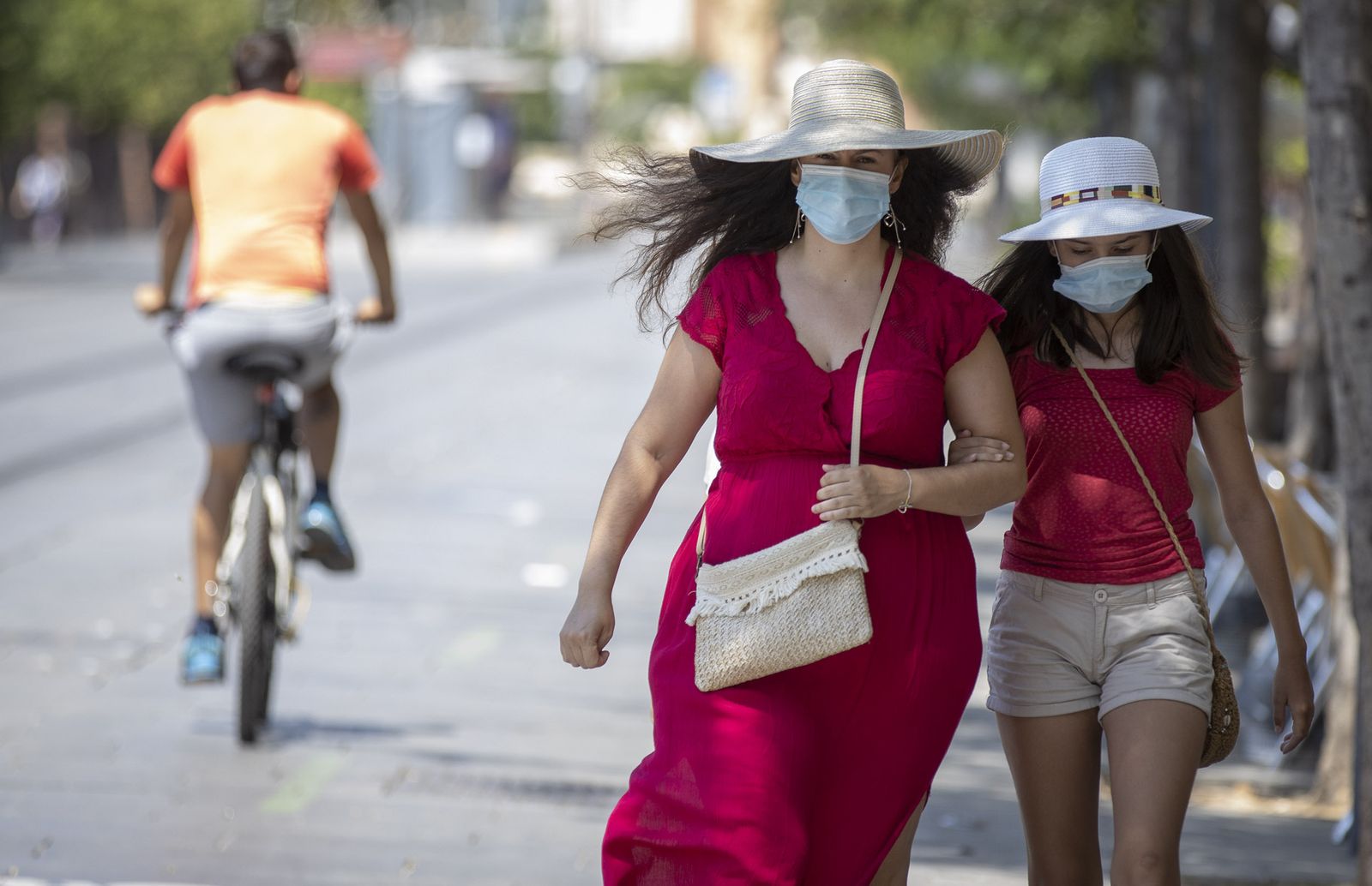 Una mujer camina junto a una menor ataviadas con mascarillas.