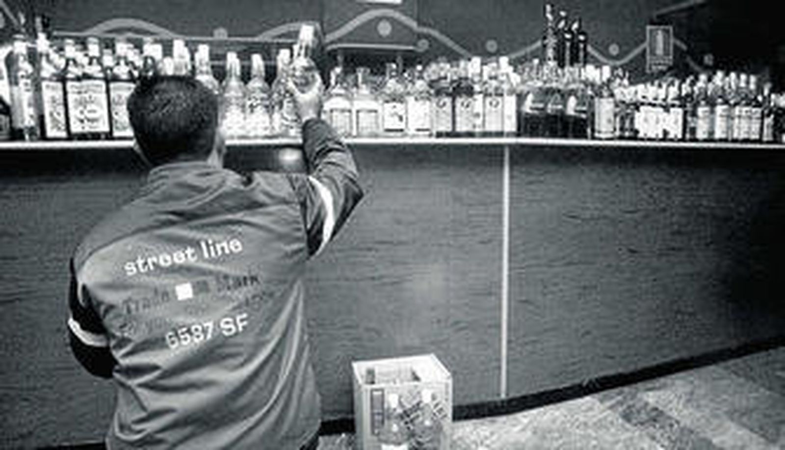 Un hombre ordena las botellas en un bar.