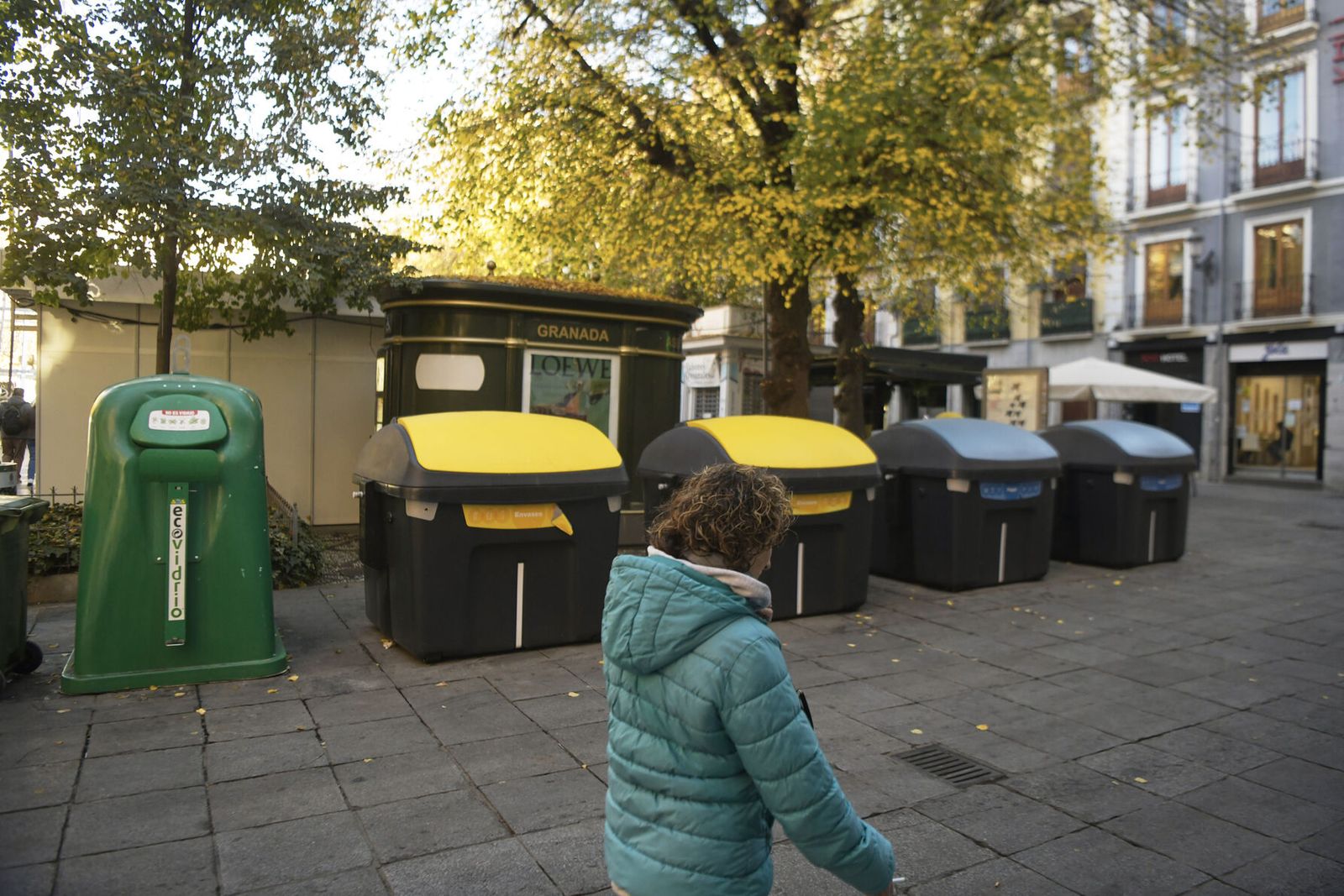 Una mujer pasa junto a varios contenedores en Plaza Bibrambla