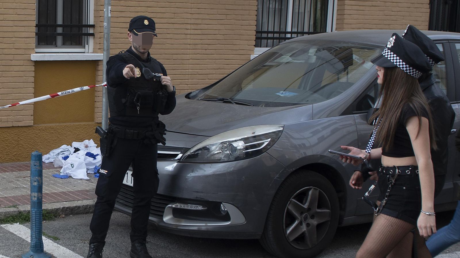 Un policía pide a unas jóvenes disfrazadas para el carnaval que pasen por otro lado.