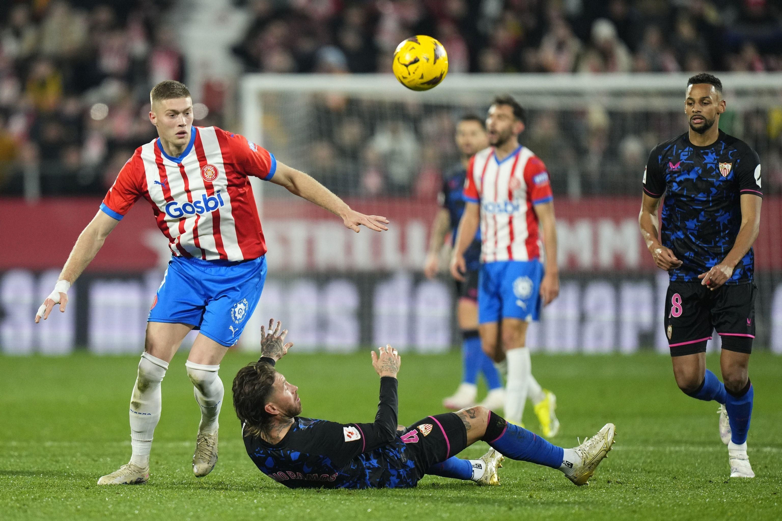 Dovbyk busca el balón con Sergio Ramos caído de espaldas en el césped.